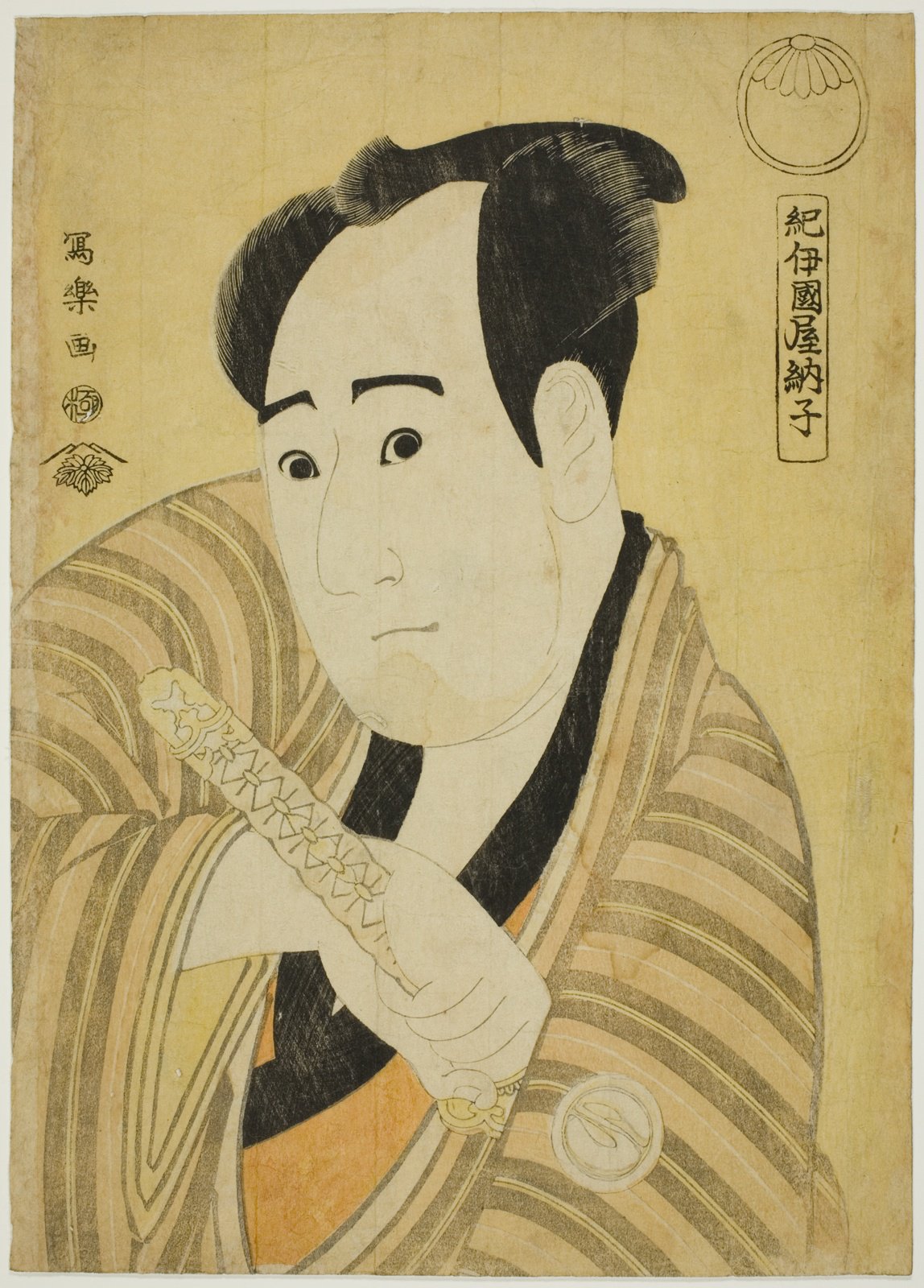 東洲斎写楽の大首絵。歌舞伎役者が刀の柄に手をかけ、こちらを見据えている。画面左に「写楽画」の落款と丸い印、右上に扇形の版元印が見える