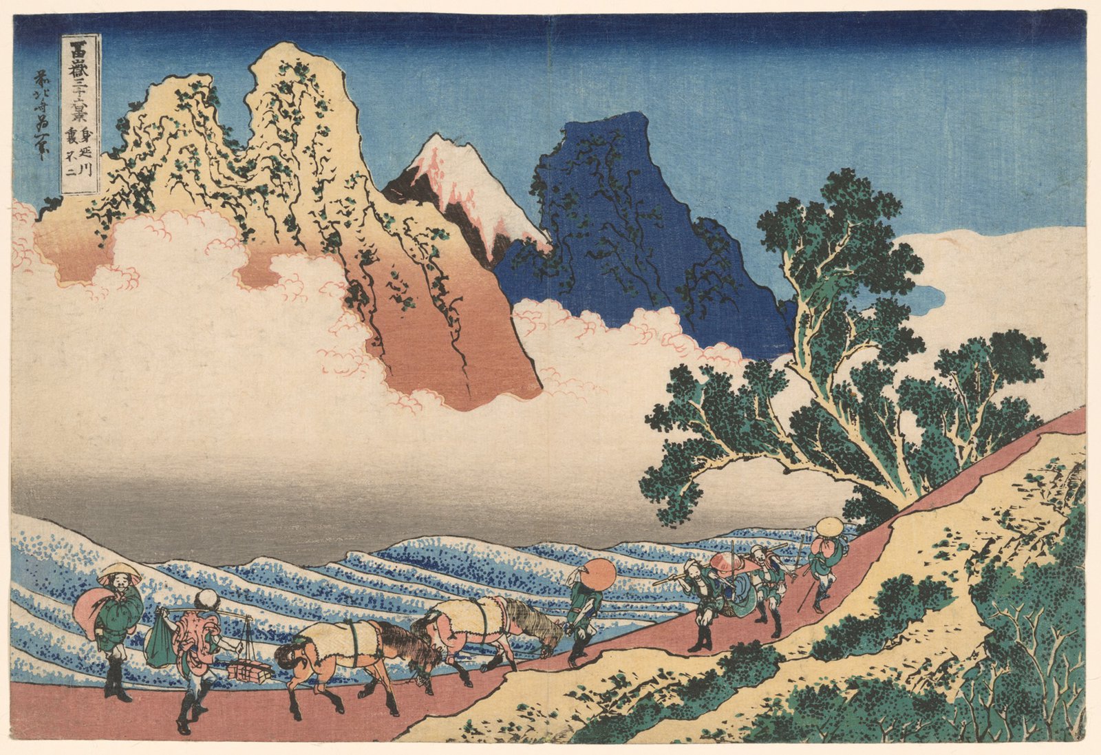 葛飾北斎「冨嶽三十六景 身延川裏不二」。旅人と荷を積んだ馬の一行が山道を進み、雲の切れ間に赤茶色と紺色に塗り分けられた山肌、その奥に雪をかぶった富士がのぞく