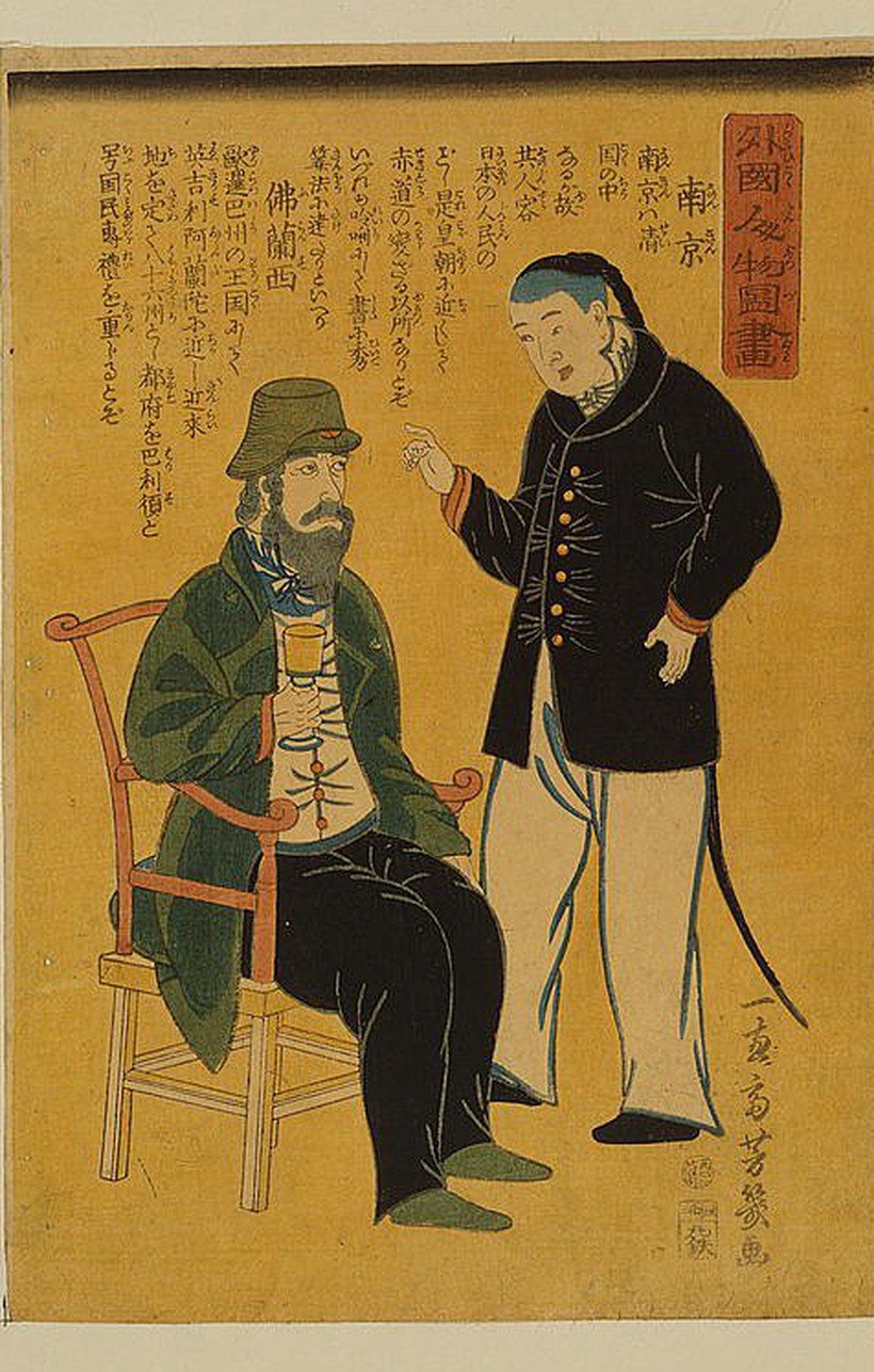 落合芳幾「外国人物図画 南京 仏蘭西」。左に緑の上着と帽子の髭の西洋人が椅子に座ってグラスを持ち、右に黒い詰襟と辮髪の中国人が立って指をさす。上部に二か国の説明文が縦書きで刷られている